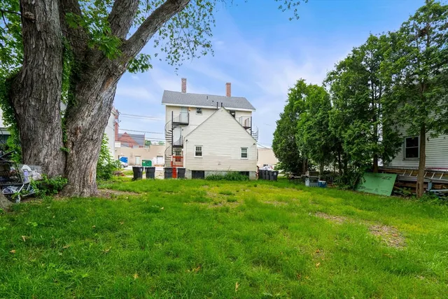 a view of a backyard with table and chairs and a large tree