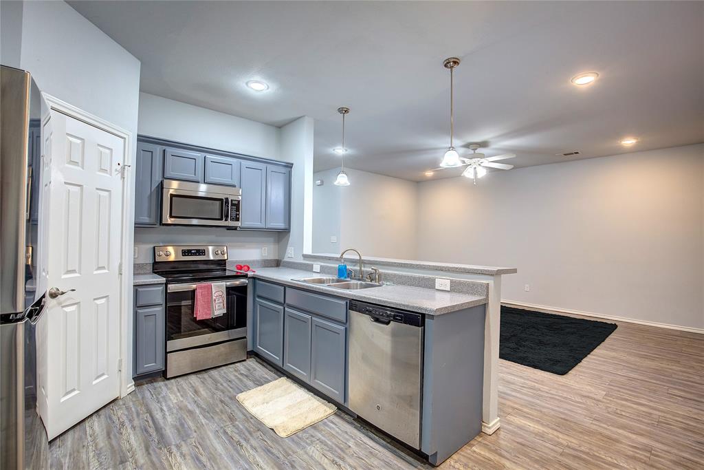1721 Division Street, Unit 1723 Commerce, TX 75428 - Photo 1 of 1 Kitchen featuring a peninsula, a sink, light wood-style floors, appliances with stainless steel finishes, and pendant lighting