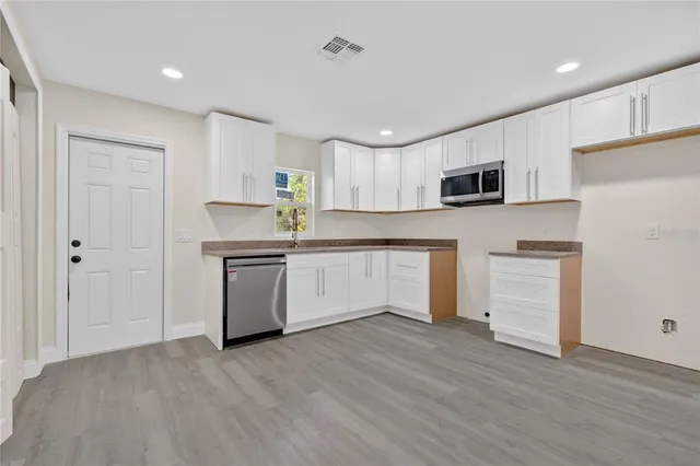a kitchen with white cabinets and stainless steel appliances
