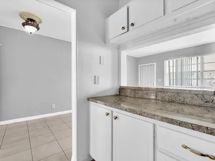 a kitchen with granite countertop a sink and white cabinets