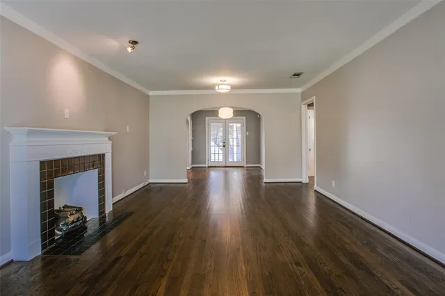 a view of an empty room with wooden floor and a fireplace