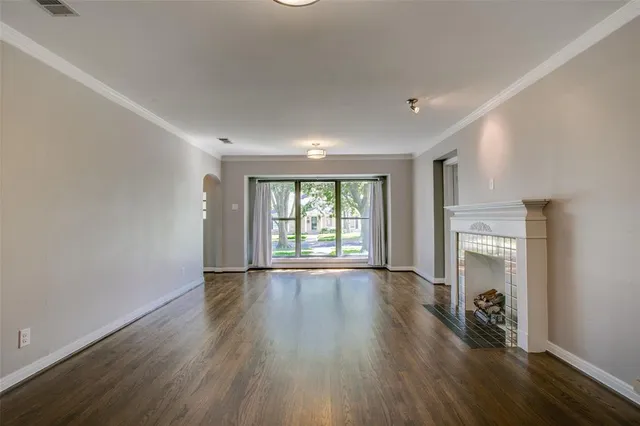 a view of an empty room with window and wooden floor