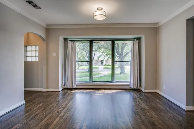 an empty room with wooden floor fireplace and windows