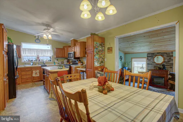 a view of a dining room and livingroom with furniture a flat screen tv a rug a fireplace and a chandelier