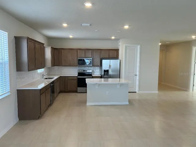 a large kitchen with kitchen island granite countertop a stove and a refrigerator
