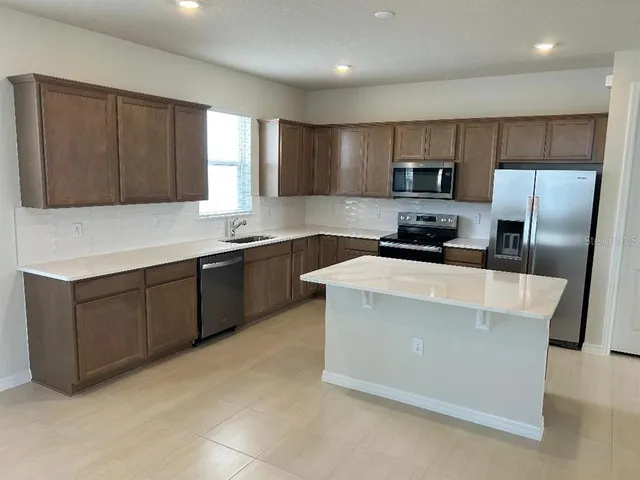 a kitchen with stainless steel appliances a refrigerator a sink a stove a microwave and wooden cabinets