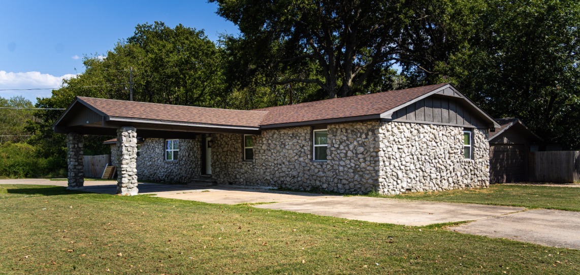 415 Martin Street Muskogee, OK 74401 - Photo 1 of 6 Stone exterior with a brown shingle roof, featuring a covered carport supported by stone pillars