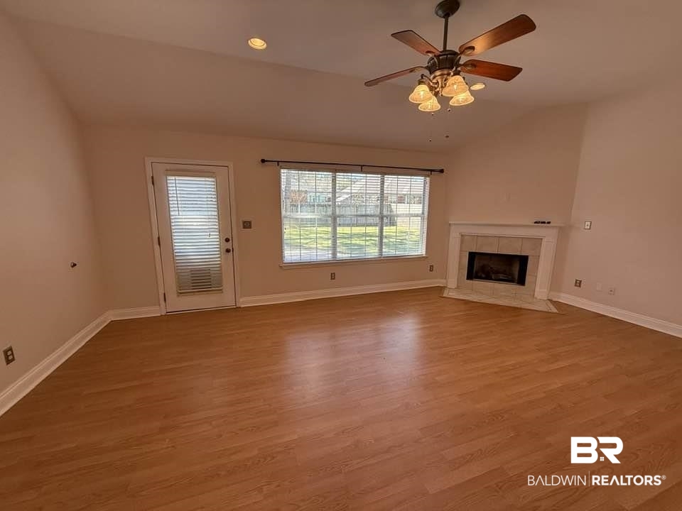 10428 South Side Loop Fairhope, AL 36532 - Photo 10 of 28 Unfurnished living room with lofted ceiling, a fireplace, baseboards, and wood finished floors