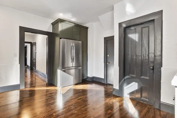 a view of a refrigerator in kitchen and livingroom with wooden floor