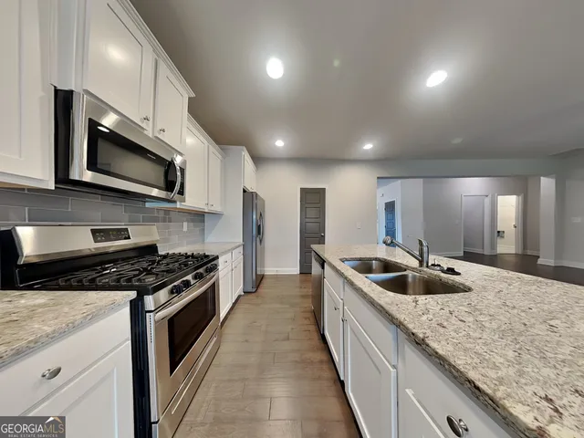 a kitchen with stainless steel appliances granite countertop a sink a stove and a wooden cabinets