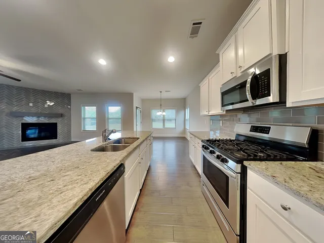 a kitchen with stainless steel appliances granite countertop a stove a sink and a microwave