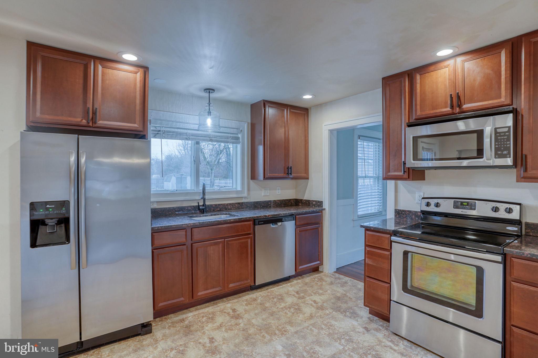129 Laurel Road Millsboro, DE 19966 - Photo 13 of 40 a kitchen with stainless steel appliances granite countertop a stove microwave and refrigerator