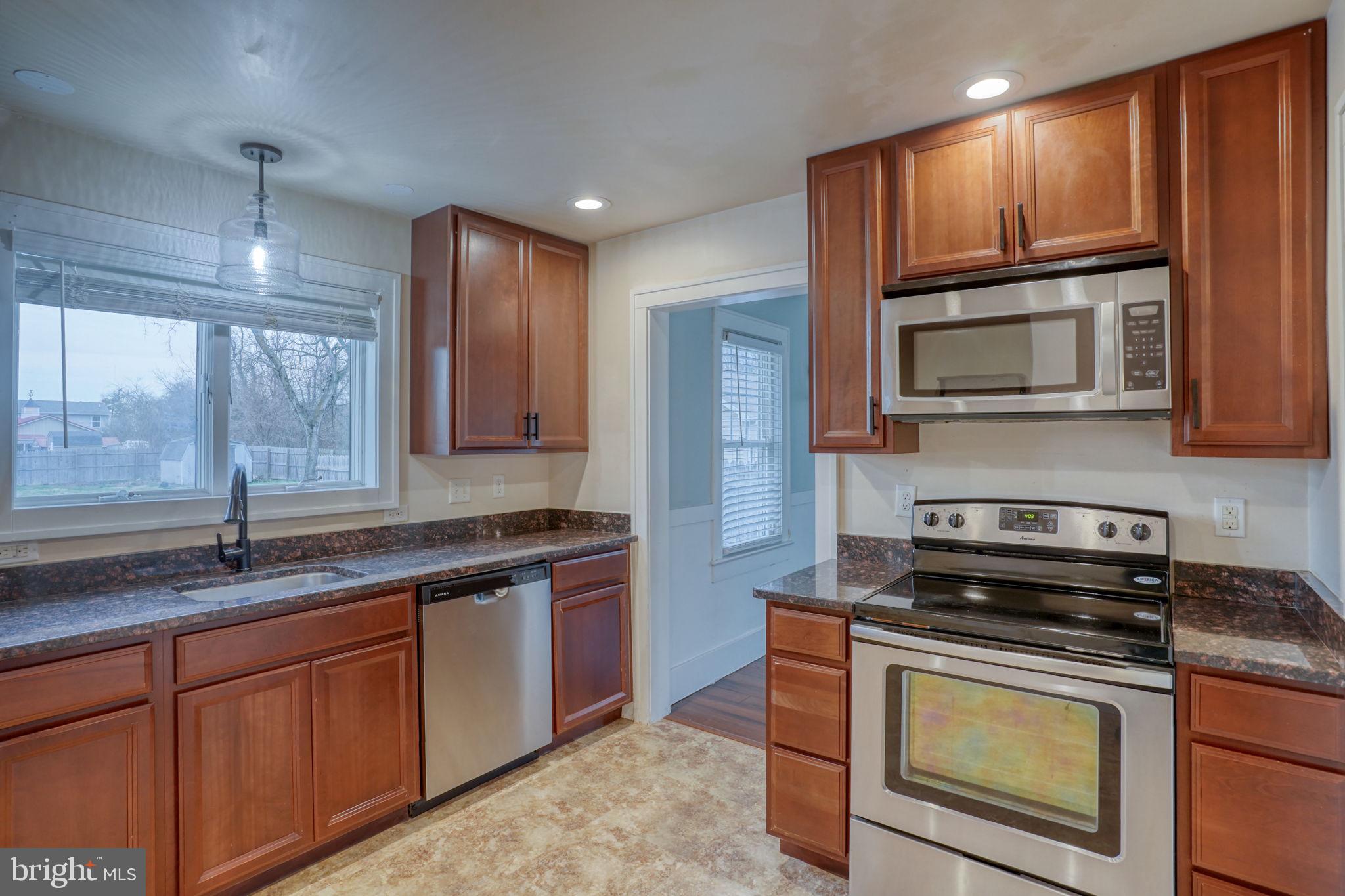 129 Laurel Road Millsboro, DE 19966 - Photo 15 of 40 a kitchen with granite countertop wooden cabinets stainless steel appliances and a window
