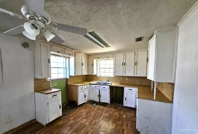 a kitchen with a stove a sink and white cabinets