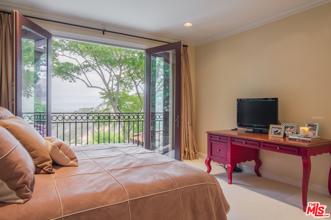 13951 Durham Road Beverly Hills, CA 90210 - Photo 20 of 29 a bedroom with a bed and a flat tv screen next to a large window