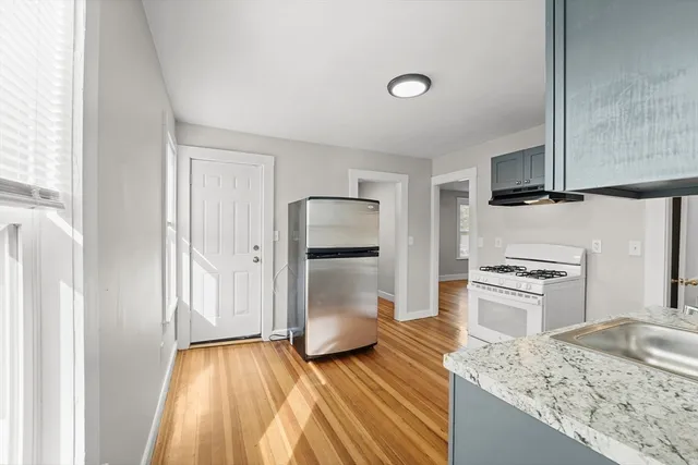 a kitchen with a refrigerator stove and wooden floor