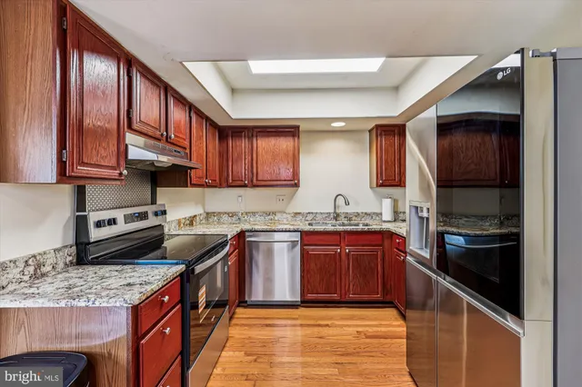 a kitchen with stainless steel appliances granite countertop a stove top oven a sink dishwasher and a refrigerator
