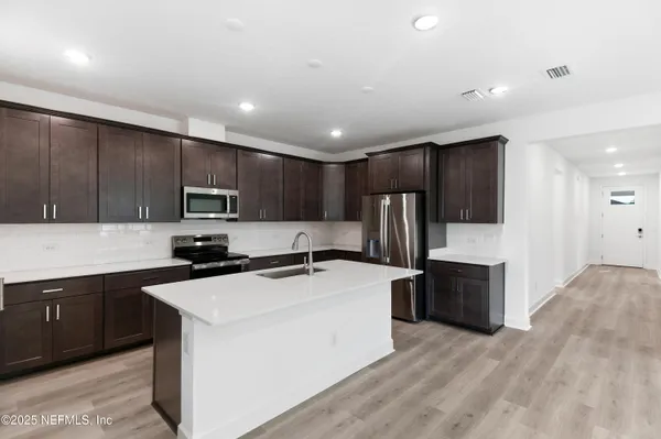 a kitchen with kitchen island a sink stainless steel appliances and cabinets