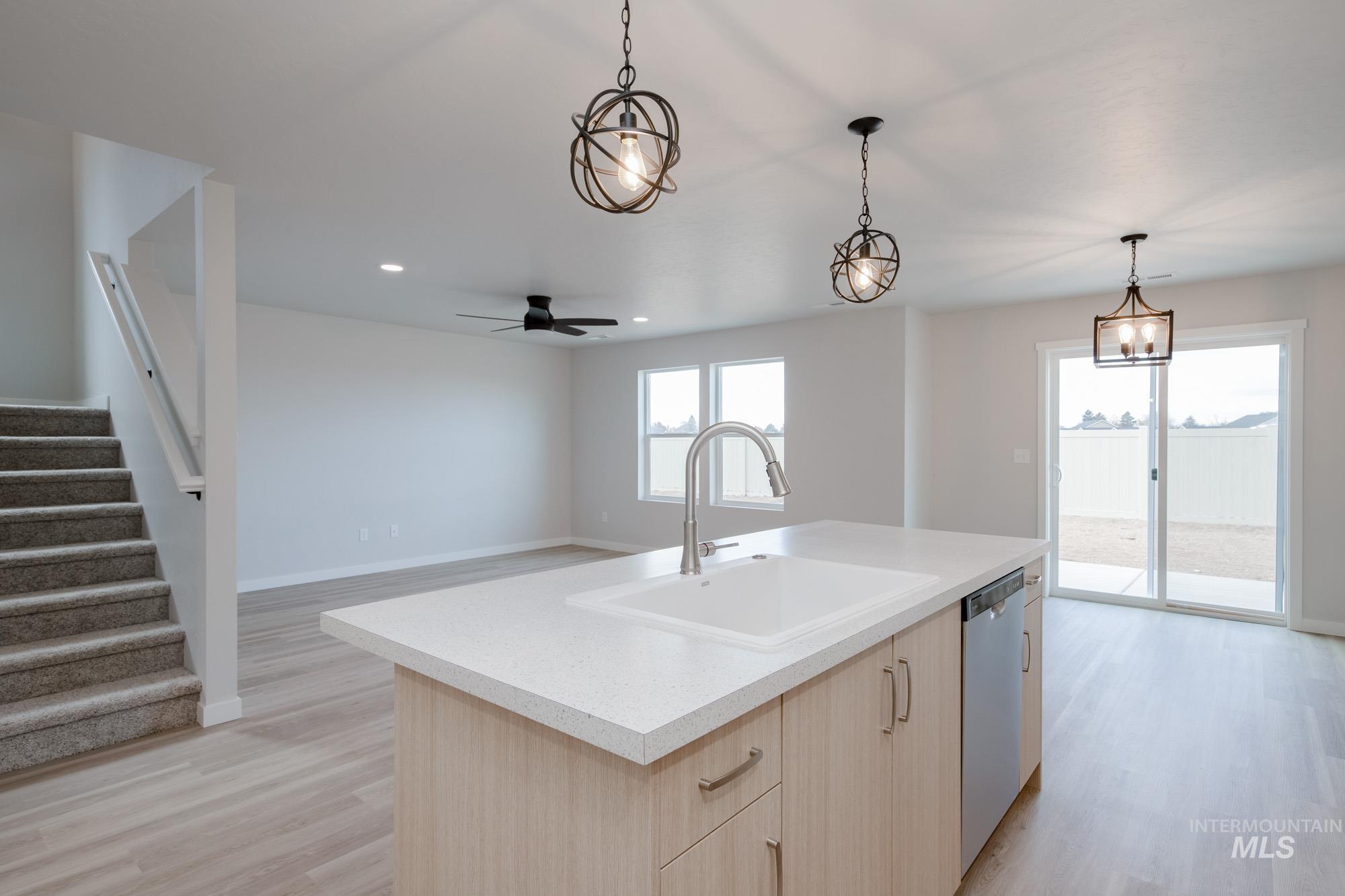 3089 South Maple Rnch Way Nampa, ID 83686 - Photo 21 of 22 Kitchen featuring light brown cabinetry, pendant lighting, light wood finished floors, open floor plan, and stainless steel dishwasher