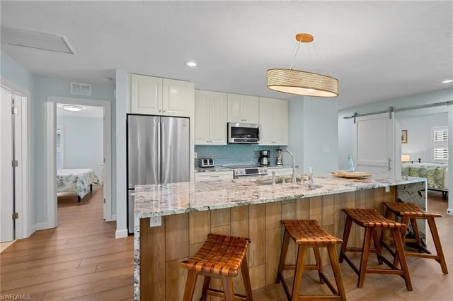 a kitchen with stainless steel appliances granite countertop a stove top oven a sink refrigerator and cabinets