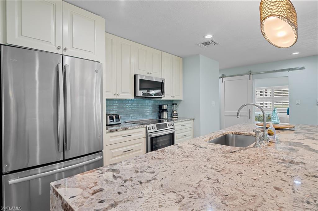 2218 Kings Lake Boulevard Naples, FL 34112 - Photo 18 of 50 a kitchen with stainless steel appliances granite countertop a refrigerator sink and stove