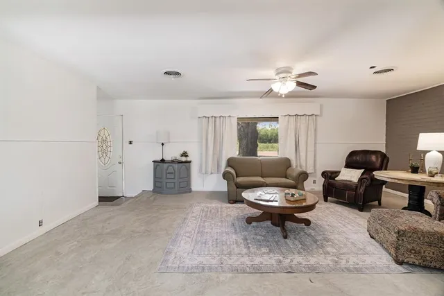 a living room with furniture a rug and a ceiling fan