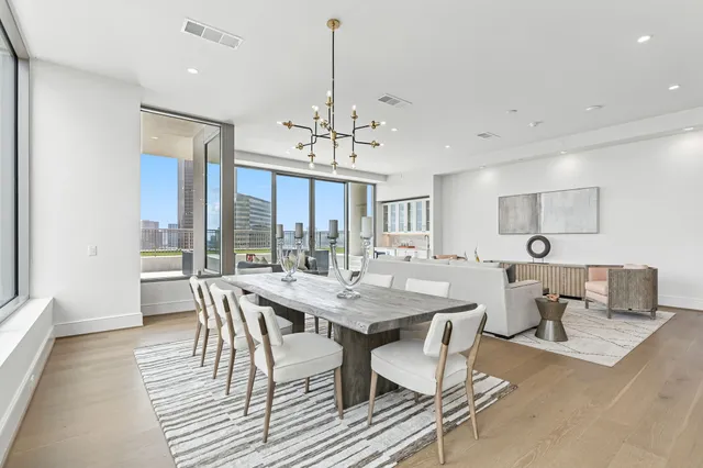 a living room with couches and kitchen view with wooden floor