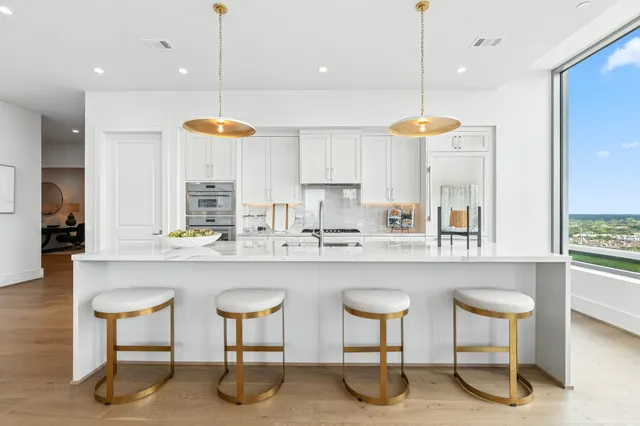 a kitchen with stainless steel appliances granite countertop a stove a sink and a chairs