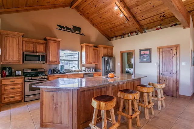 a kitchen with stainless steel appliances granite countertop a stove a sink dishwasher and a refrigerator with wooden cabinets