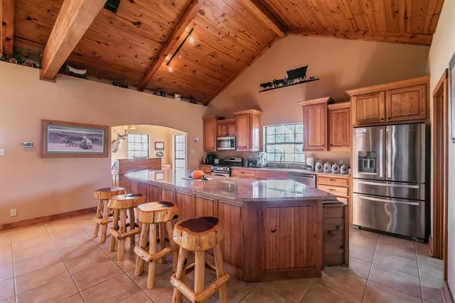 a kitchen with stainless steel appliances granite countertop a table chairs and a refrigerator