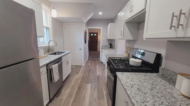 a kitchen with granite countertop a stove a sink a refrigerator and wooden cabinets