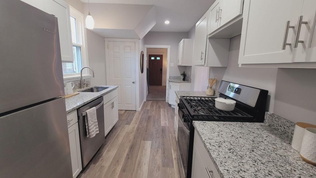 2907 Main Street Homestead, PA 15120 - Photo 6 of 14 a kitchen with granite countertop a stove a sink a refrigerator and wooden cabinets