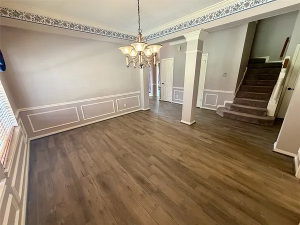 a view of kitchen with an empty room and wooden floor
