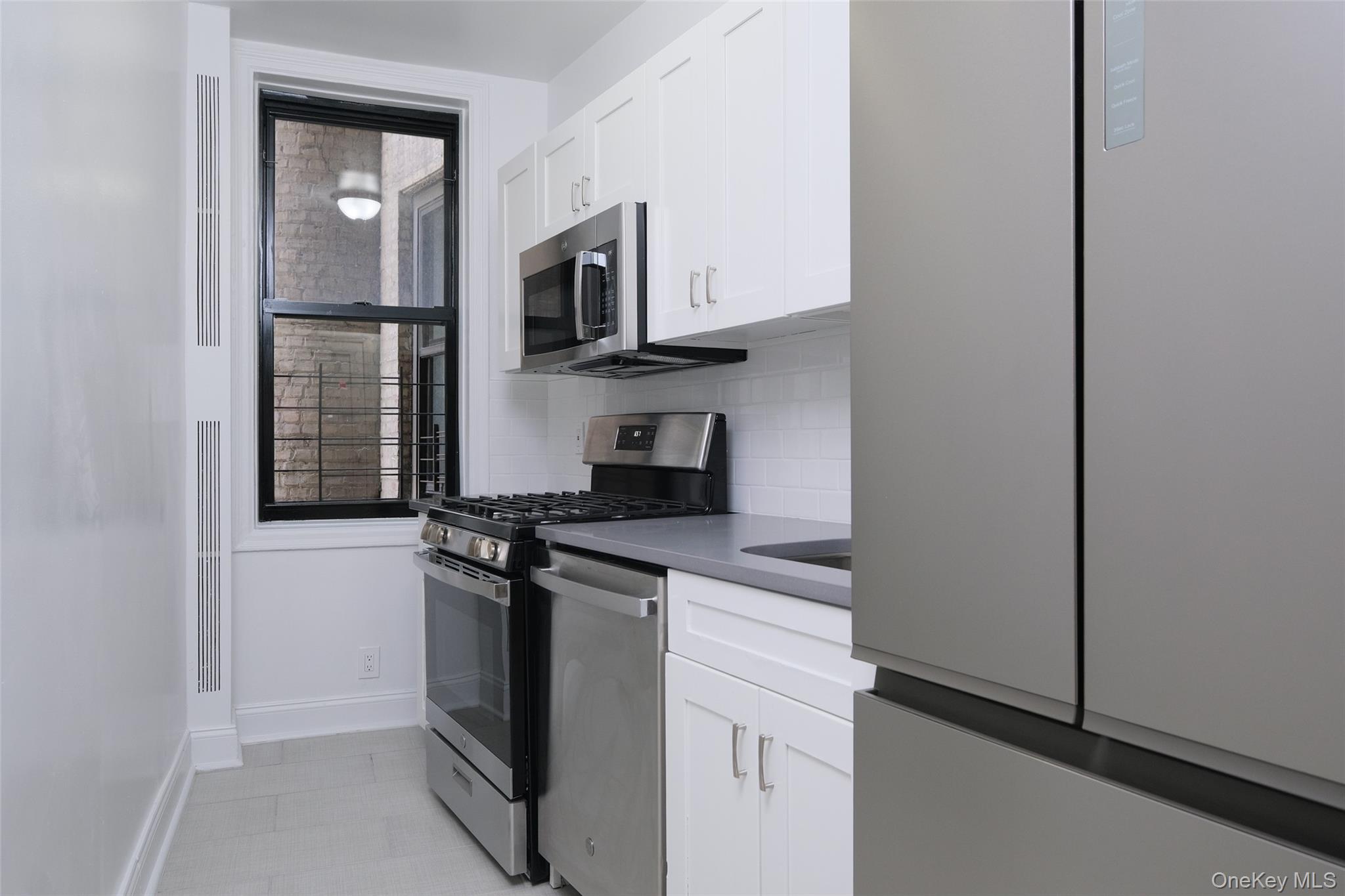 340 East Mosholu Parkway South, Unit 1A Bronx, NY 10458 - Photo 6 of 10 a kitchen with stainless steel appliances granite countertop white cabinets and black appliances