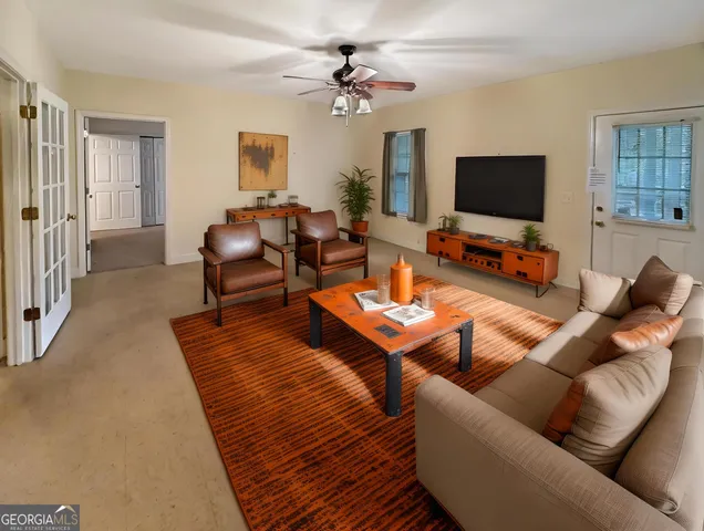 a living room with furniture a flat screen tv and a window