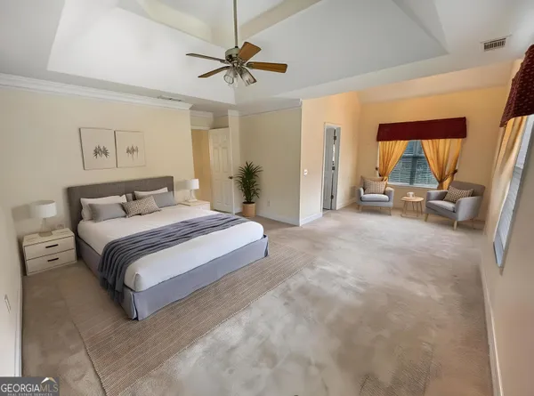 a spacious bedroom with a bed a couch and a chandelier