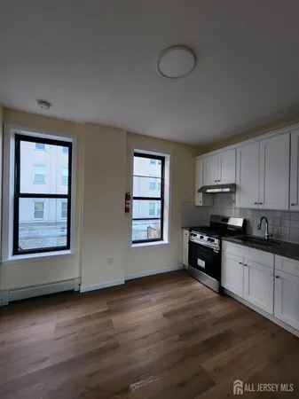 a kitchen with granite countertop a stove top oven a sink and dishwasher with wooden floor