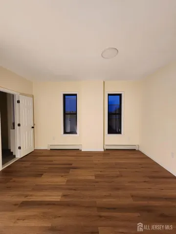 a view of an empty room with wooden floor and window