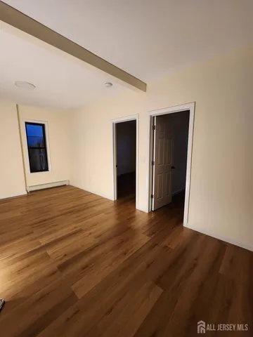 a view of an empty room with wooden floor and closet