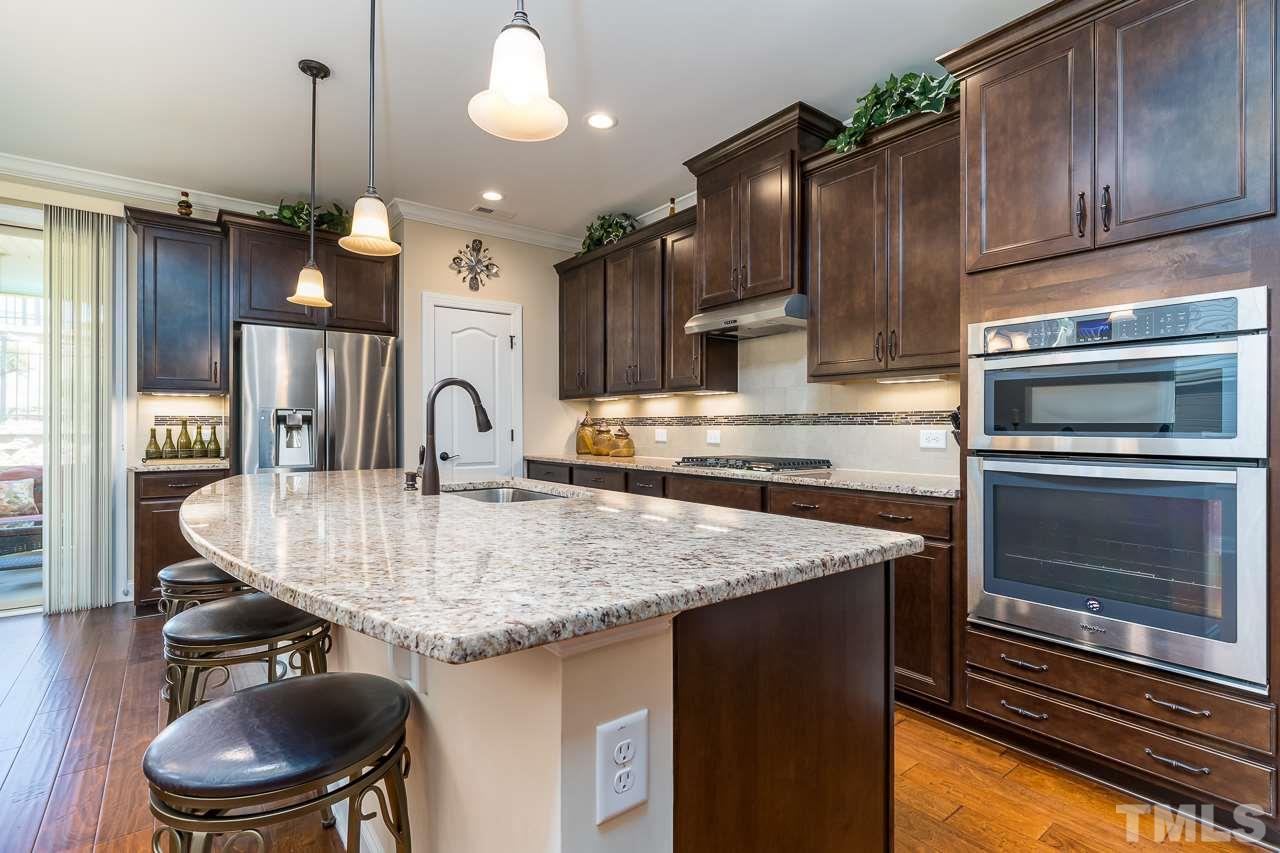 1524 Catch Fly Lane Durham, NC 27713 - Photo 7 of 25 a kitchen with kitchen island granite countertop a stove a sink and a refrigerator