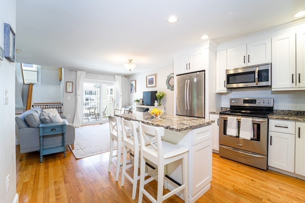 a kitchen with stainless steel appliances granite countertop a stove refrigerator and a view of living room