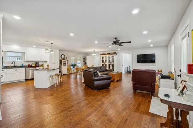 a living room with furniture kitchen view and a wooden floor