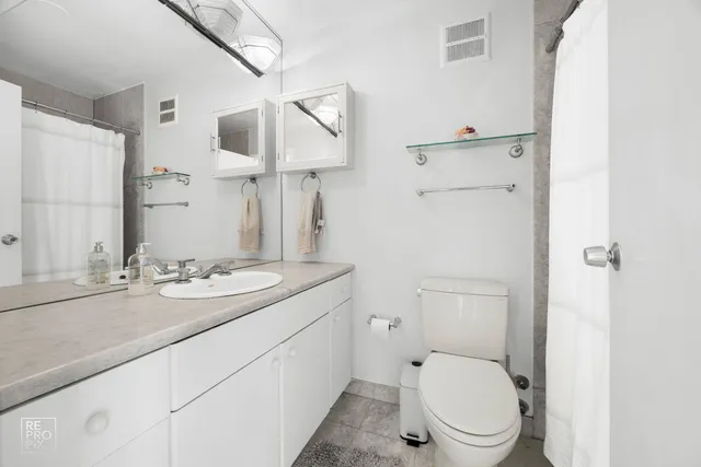 a bathroom with a granite countertop toilet sink and mirror