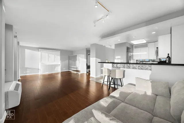 a living room with couches and kitchen view with wooden floor