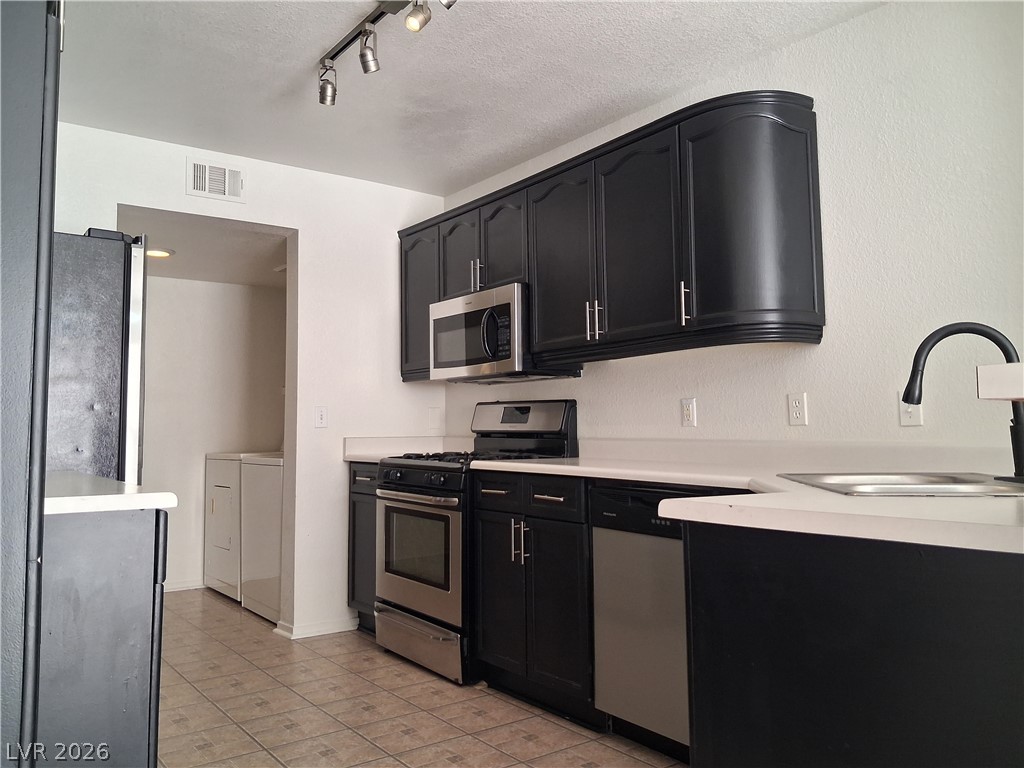 8023 Simone Avenue Las Vegas, NV 89147 - Photo 5 of 12 A well-appointed kitchen features dark cabinetry with stainless steel appliances and an integrated sink.