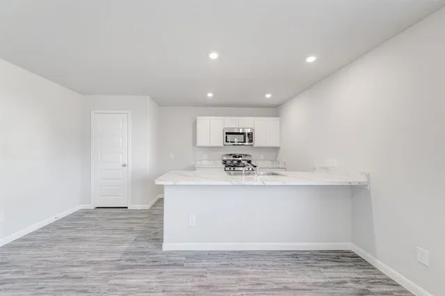 a view of kitchen with stainless steel appliances granite countertop a sink and a refrigerator