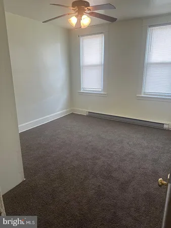 an empty room with windows and fan