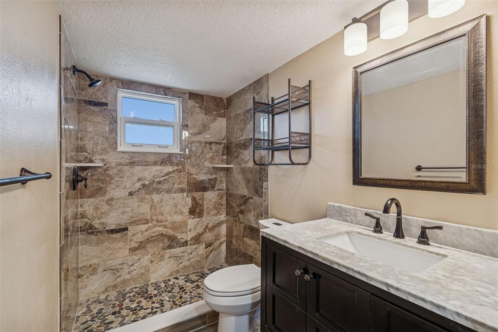 4937 Marine Parkway, Unit 105 New Port Richey, FL 34652 - Photo 18 of 50 a bathroom with a granite countertop sink toilet and shower