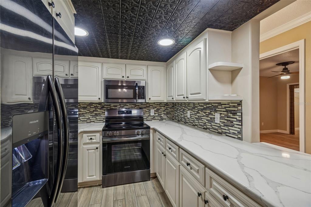 4937 Marine Parkway, Unit 105 New Port Richey, FL 34652 - Photo 9 of 50 a kitchen with kitchen island granite countertop a stove and a refrigerator