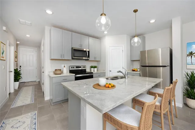 a kitchen with a refrigerator a stove a sink and a dining table with chairs